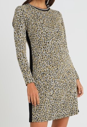 Mujer que lleva un vestido de manga larga hasta la rodilla con estampado de leopardo, paneles laterales negros y escote a rayas.