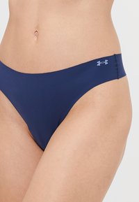 Marineblauwe bikini onderkant van gladde stof, met een laag uitgesneden ontwerp en een klein lichtblauw logo aan de rechterkant.