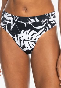 Černé bikiny s vysokým pasem a velkým bílým tropickým listovým vzorem, vyrobené z elastického materiálu s hladkou texturou a kontrastním prošíváním.