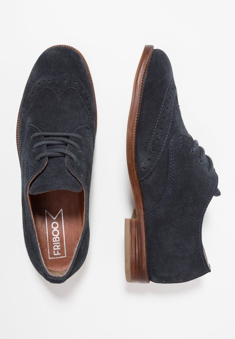 Granatowe zamszowe buty oxford z okrągłym noskiem, sznurowanym zapięciem, detalami brogu oraz brązową gumową podeszwą. Gładka skórzana podszewka.