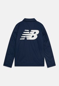 Mornarska jakna s velikim bijelim New Balance logotipom na leđima, s ovratnikom i dugim rukavima od glatkog, teksturiranog materijala.