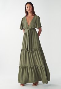 Olivenfarbendes Maxikleid mit tiefem V-Ausschnitt, kurzen Puffärmeln, Bindegürtel und gestuftem Rockdesign, aus leichtem strukturiertem Stoff gefertigt.