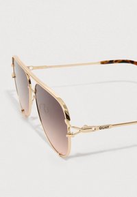 Guldtonede pilot-solbriller med gradient grå linser, der har en elegant metalramme, skildpaddeskalsfarvede stangsider og indgraveret mærke.