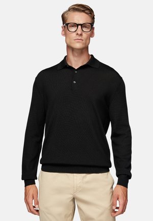 Polo de manga larga negro con tejido texturizado, que presenta una tapeta de tres botones y puños de canalé. Diseño liso, silueta ajustada.
