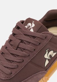 Baskets en tissu marron avec surface texturée, dotées de lacets assortis, d'un accent de logo et d'une semelle en caoutchouc gomme.