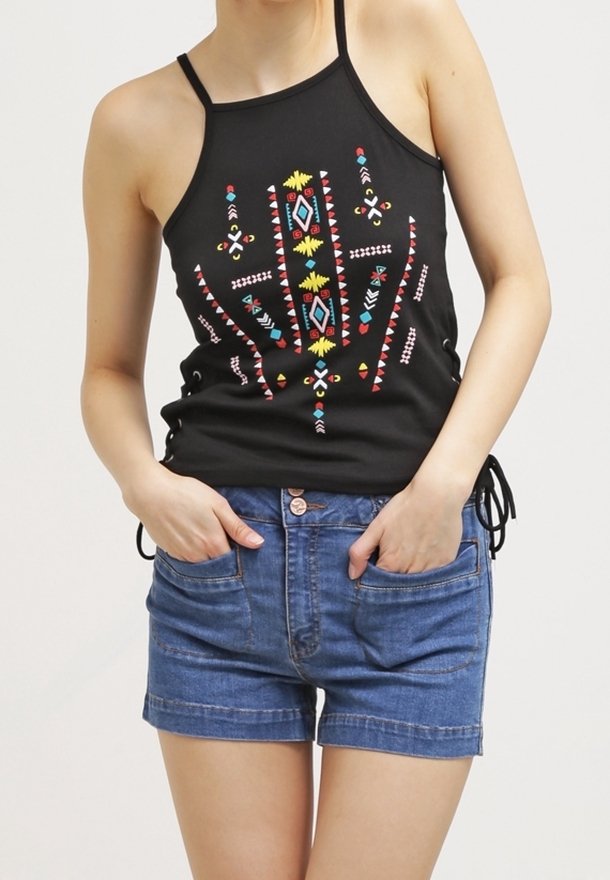 Mustat halterneck-topit, joissa on värikkäitä geometrisia kirjontoja, yhdistettynä farkkushortseihin, joissa on etutaskut ja käännetty helma.