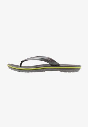 Sort flip-flop sandal med en tekstureret fodseng, fleksible stropper og et grønt accentbånd langs sålen. Letvægts og afslappet design.