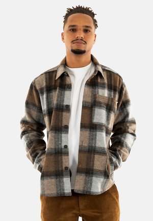 Brun og grå ternet flannel skjorte med knaplukning foran, spredt krave og lange ærmer, parret med en hvid t-shirt under.