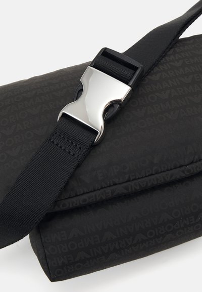 Črna crossbody torba iz najlona z diskretno embosirano logotipno vzorcem, nastavljivim trakom in kovinsko sponko.