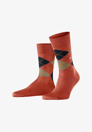 Rote und marineblaue Socken im Argyle-Muster mit einem gerippten Bündchen, glatter Textur und einem kleinen dekorativen Logodetail in der Nähe des Knöchels.