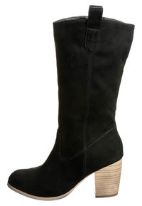 Bota alta de gamuza negra hasta la rodilla con punta redonda y un tacón de bloque de madera texturizada. Presenta costuras mínimas y una pestaña en la parte posterior.
