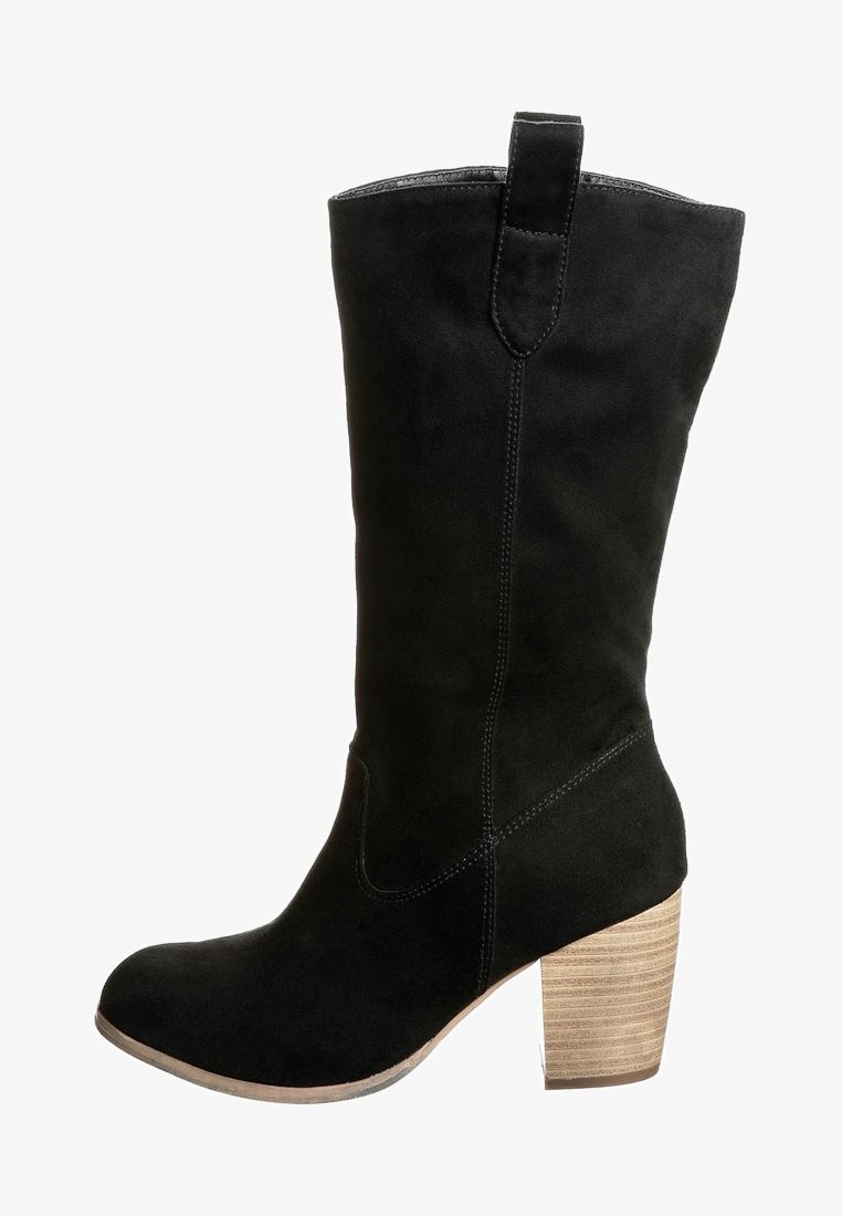 Bota alta de gamuza negra hasta la rodilla con punta redonda y un tacón de bloque de madera texturizada. Presenta costuras mínimas y una pestaña en la parte posterior.