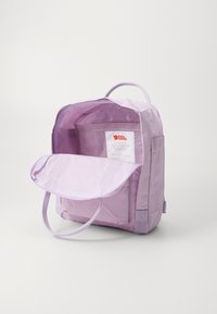Lichtpaarse rugzak met een voorflap, een stoffen lus handvat en verstelbare schouderbanden. Interieur heeft een label en een zak. Gladde textuur.