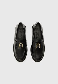 Black leather loafers with a rounded toe, featuring a gold-tone monogram hardware accent and textured rubber sole.