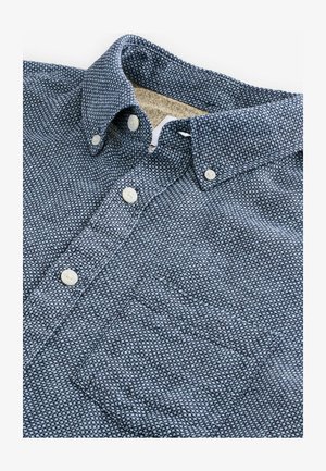 Cămașă cu nasturi, din material cu model albastru și alb. Are guler, un buzunar frontal și nasturi albi. Detalii de țesătură texturată vizibile.