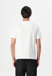 White cotton t-shirt with short sleeves, round neckline, and a relaxed fit; minimalistic design with no patterns or accents.