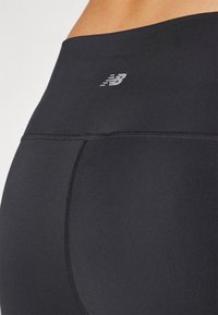 Leggings de entrenamiento negros de cintura alta con una textura suave, presentan un logo gris y costuras planas, diseñadas para comodidad y flexibilidad.