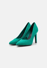 Décolleté in suede teal con punta affusolata, texture liscia e tacchi a stiletto sottili. Presentano un taglio aperto attorno alla caviglia.