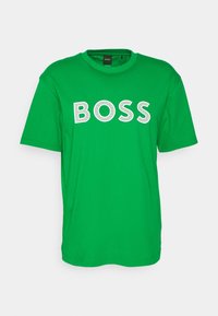 Zelené bavlněné tričko s kulatým výstřihem a krátkými rukávy. Na hrudi je velký nápis "BOSS" v bílé barvě.