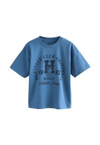 Modrá bavlněná tričko s krátkými rukávy, se grafickým potiskem v tmavě modré a černé barvě, včetně nápisu "HERITAGE CLUB ORIGINALS" a loga.