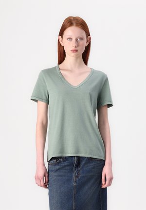 Grønn v-hals t-skjorte med korte ermer, laget av myk stoff. Enkelt design med en avslappet passform. Bæres med et denimskjørt.