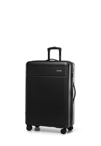 Zwarte harde koffer met verticale ribbeltextuur, uitschuifbare handgreep en vier wielen voor mobiliteit. Bevat het merkembleem aan de voorkant.