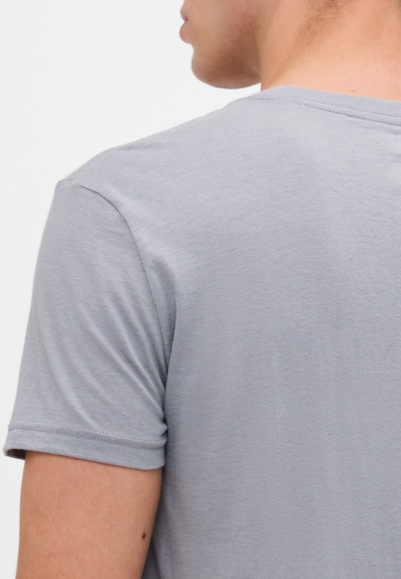 Graues T-Shirt mit kurzen Ärmeln aus weicher Baumwolle, mit Rundhalsausschnitt und glatter Textur. Minimale Nähdetails an den Ärmeln.