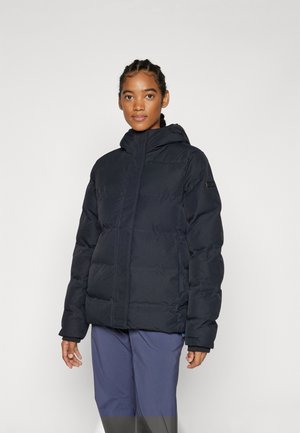 Padded black jacket with a zip front and hood, featuring a textured fabric and subtle branding on the sleeve. Worn over dark pants.