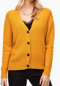 Senapsgul ribbad cardigan med en djup V-halsringning, med sex svarta knappar fram och långa ärmar. Mjuk stickad textur.