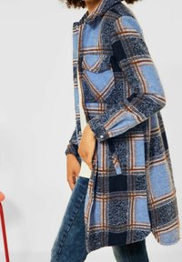 Camisa chaqueta de manga larga a cuadros en azul, marino y marrón. Textura de franela, frente abotonado, bolsillo en el pecho y bolsillos laterales.