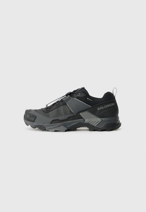 Black trail running shoe with a durable mesh upper, reinforced toe cap, textured rubber sole, and elastic lacing system for secure fit.