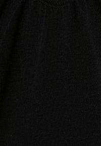Tecido de malha canelada preta com uma textura suave, apresentando um leve stretch e um acabamento liso. O material parece uniforme e consistente.