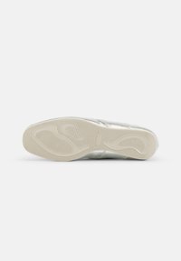 Metallisk sølv sneaker med en teksturert overflate og en sporadisk hvit gummisåle. Har minimalistisk design og en glatt overflate.