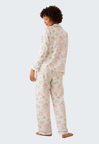 Lättvikts, pastellfärgade pyjamas med fantasifulla matmönster. Inkluderar en långärmad topp och löst sittande byxor med kontrasterande kanter.