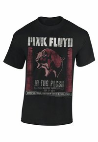 Camiseta de algodón negra con un diseño gráfico de un cerdo sobre un fondo rojo, con "PINK FLOYD" y detalles del concierto en texto grueso.