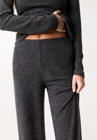 Ensemble de détente gris texturé composé d'un haut à manches longues et d'un pantalon assorti, fabriqué en tissu doux et confortable avec une taille élastique.
