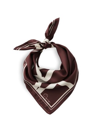 Femme aux cheveux courts et bruns porte une veste foncée et une écharpe bordeaux et blanche à motifs autour du cou, regardant légèrement sur le côté.