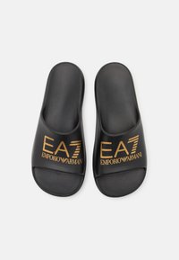 Black slide sandals made of smooth synthetic material featuring a wide strap with gold "EA7 EMPORIO ARMANI" logo. Flat sole, open design.