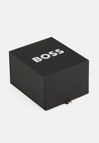 Scatola nera con finitura opaca, caratterizzata da un testo bianco in grassetto "BOSS" sulla parte superiore. Ha una chiusura magnetica e una texture sottile sui lati.