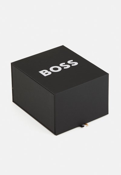 Черна кутия с матово покритие, с изразителен бял текст "BOSS" отгоре. Разполага с магнитно затваряне и ненатрапчив текстурен модел отстрани.