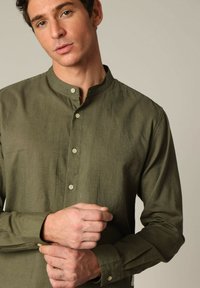 Olijfgroene, langemouwenshirt met een bandkraag en knoopsluiting, met een gestructureerde stof en zichtbare stiksels.