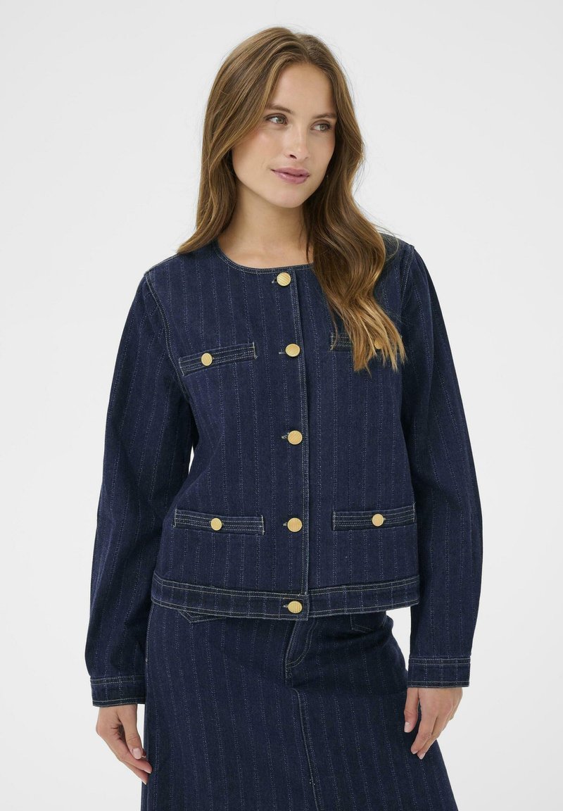 Námornícky modrá džínová bunda s okrúhlym výstrihom, zlatými gombíkmi a dvoma prednými vreckami, so vertikálnym prešívaním a skráteným strihom.