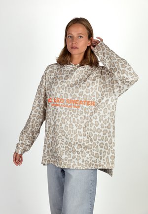 Beige und hellbraune Oversized-Hoodie mit Leopardendruck, ausgestattet mit einer Fronttasche und orangefarbenem Text. Hergestellt aus weichem, strukturiertem Stoff.