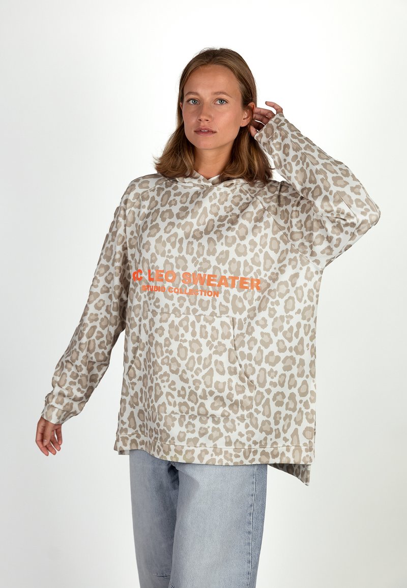 Leopard print oversized hoodie in beige and light brown, featuring a front pocket and orange text. Made from soft, textured fabric.
