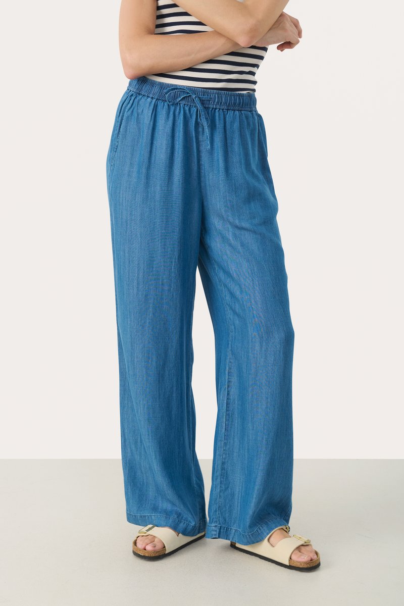 Breda ben, blå denimbyxor med elastisk midja och snörning. Mjuk textur, avslappnad passform och något avsmalnande öppning vid ankeln.