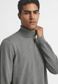 Szary sweter z golfem wykonany z teksturowanej dzianiny. Posiada wysoki kołnierz i długie rękawy, co zapewnia dopasowany wygląd.