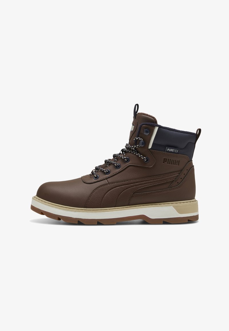 Brązowy skórzany but marki Puma w stylu wysokim z czarnym kołnierzem, wzorzystymi sznurowadłami, beżową podeszwą i etykietą PureTex z boku, przedstawiony w profilu, z prawej strony.