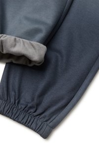 Donkergrijze joggers met een zachte, elastische boord van een lichter grijze stof, met een gladde textuur en contrasterende stikdetails.