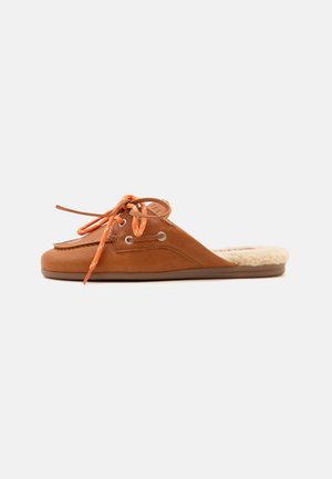 Chaussure à enfiler en cuir marron avec des lacets orange et une semelle intérieure douce et duveteuse couleur crème, vue de côté sur un fond uni.