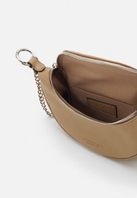 Borsa in pelle marrone con accessori in metallo argentato, dotata di chiusura zip e interno con tasca per carte; texture liscia e forma arrotondata.